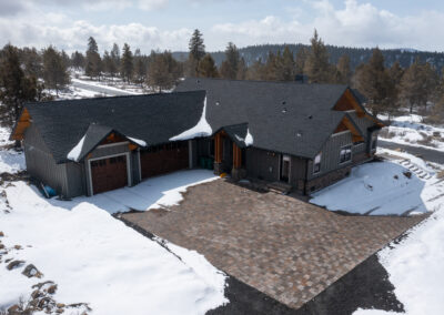 Photo of custom home with paver driveway with snow surrounding.
