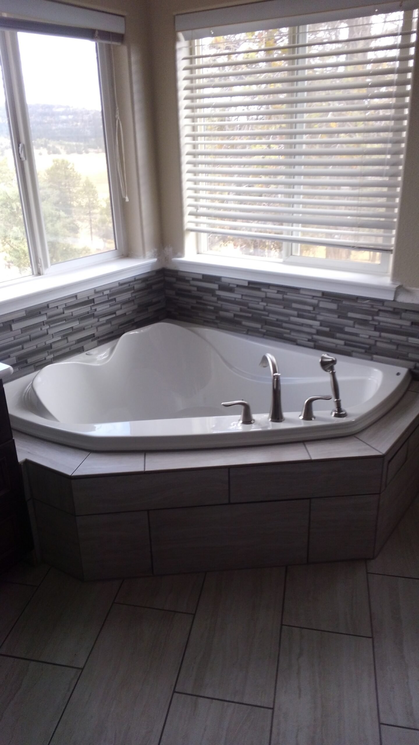 Corner bathtub beneath two windows