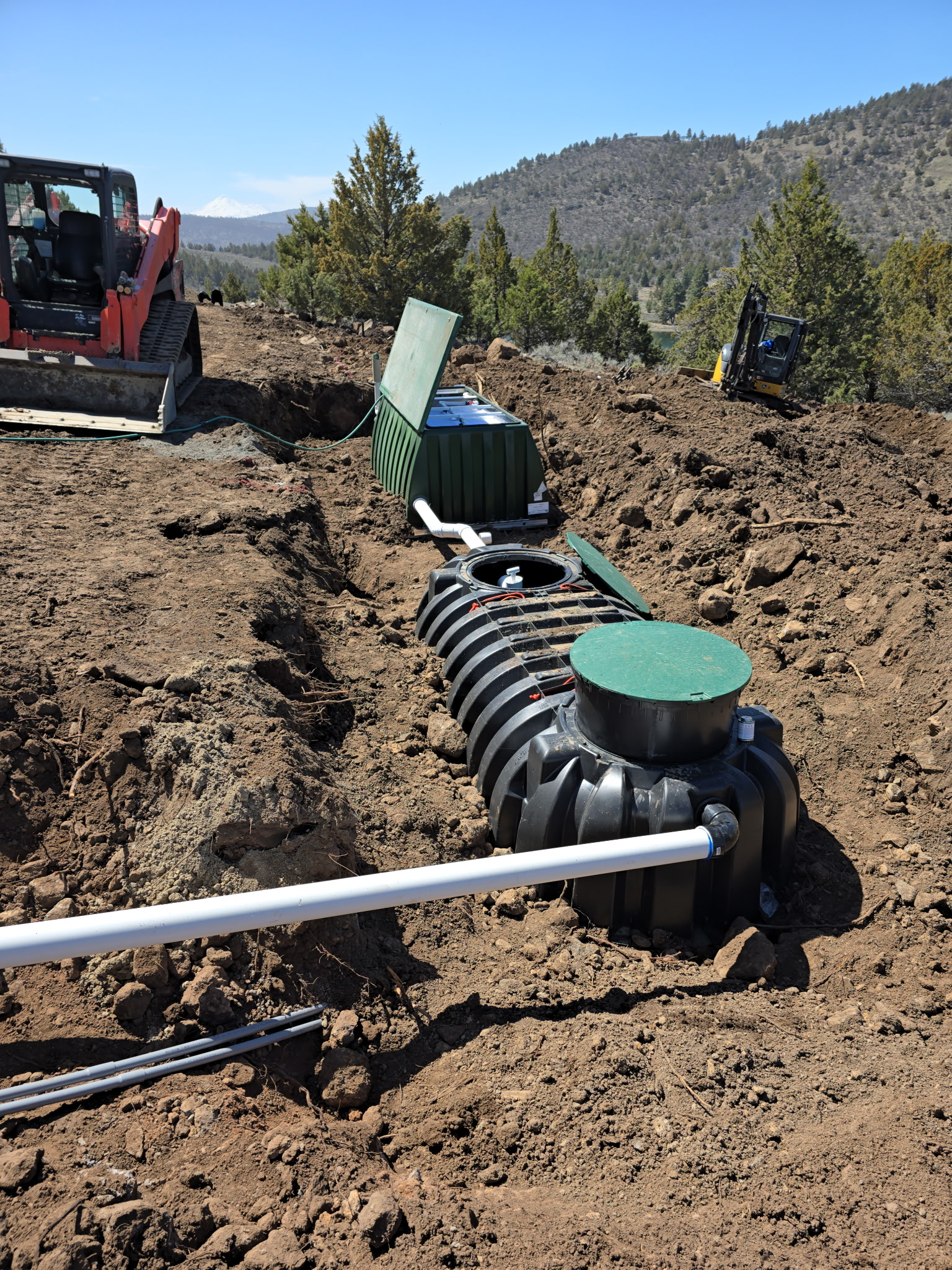 Septic tank installation with excavation equipment on a rural Southern Oregon site