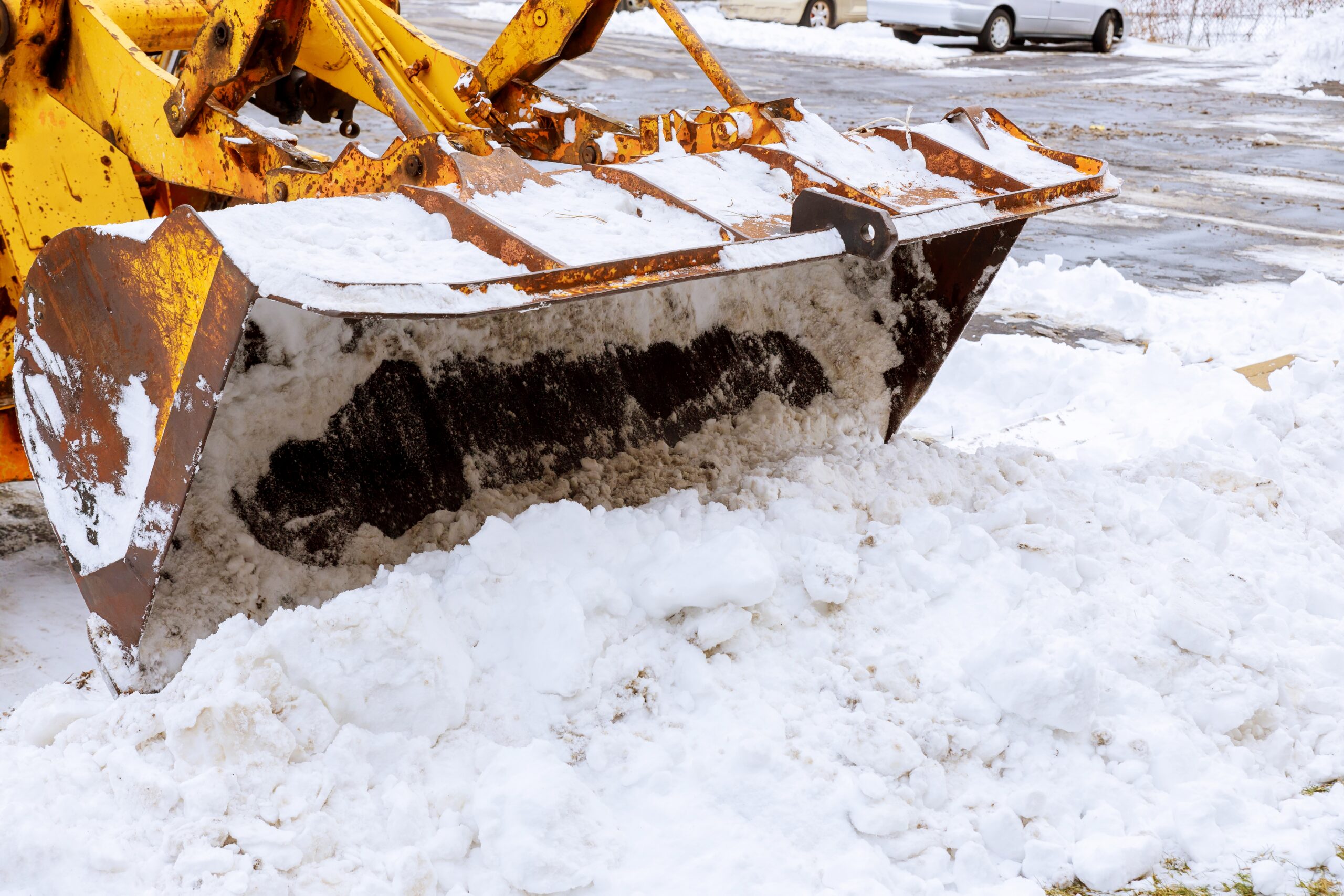 Yellow snowplow clearing snow from a parking lot